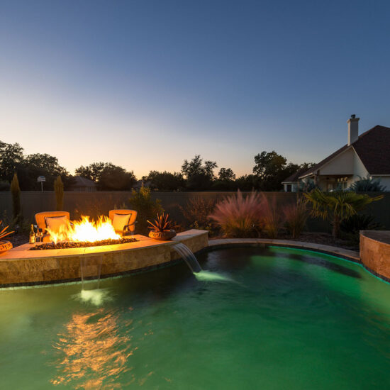 Pebble Tec Pool Colors create a green lagoon with a custom fire pit.