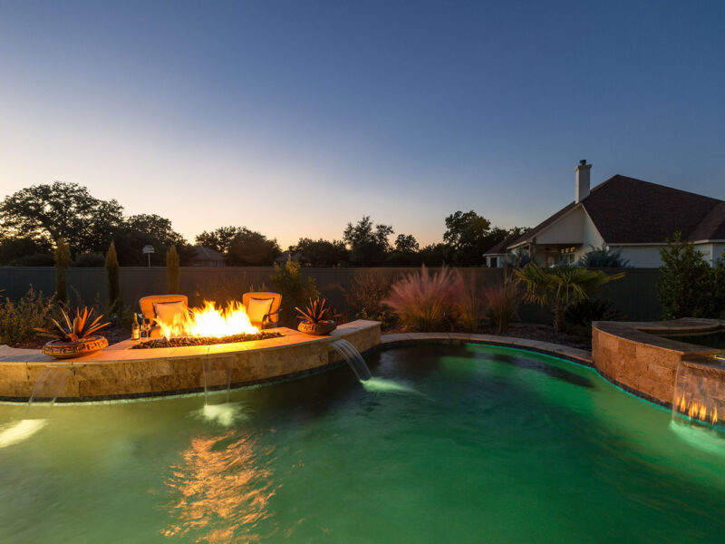 Pebble Tec Pool Colors create a green lagoon with a custom fire pit.