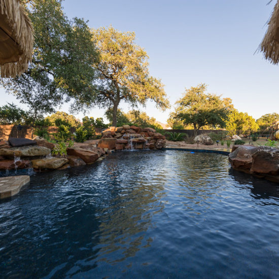 This relaxing backyard retreat and poolscape in San Antonio creates a tropical atmosphere.