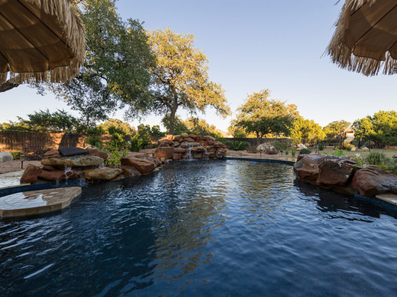 This relaxing backyard retreat and poolscape in San Antonio creates a tropical atmosphere.