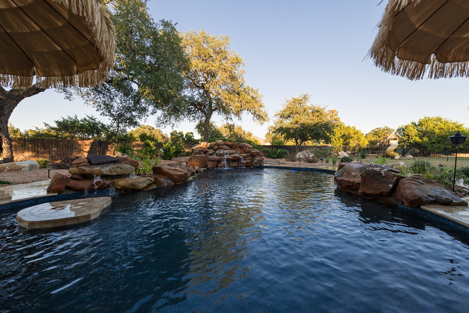 This relaxing backyard retreat and poolscape in San Antonio creates a tropical atmosphere.