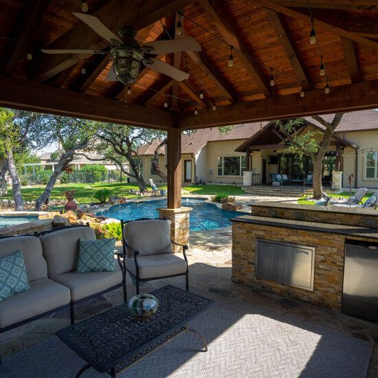 This custom poolscape features a relaxing backyard kitchen and outdoor living space.