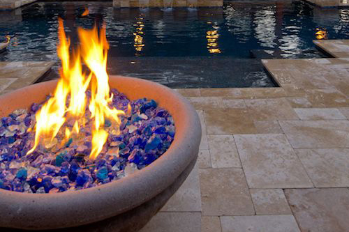 A fire bowl next to a modern pool design